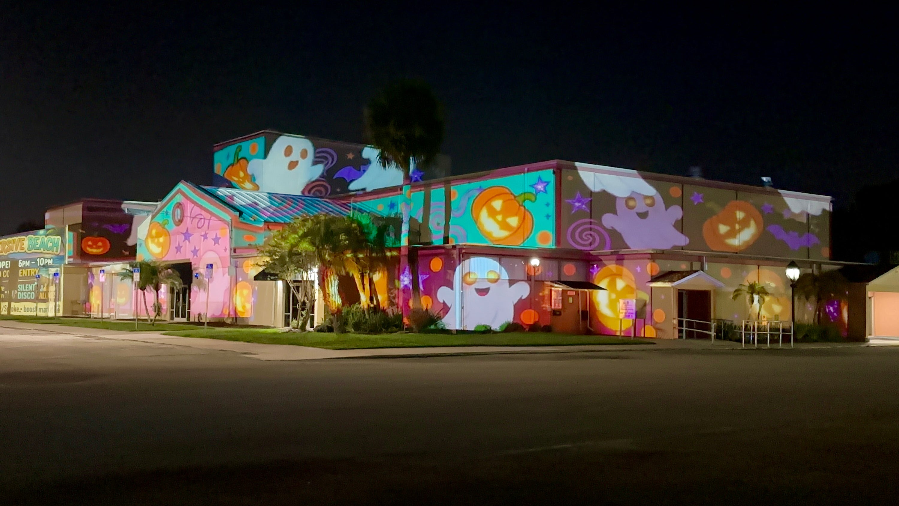 Colorful Halloween ghosts and pumpkins projected onto a building